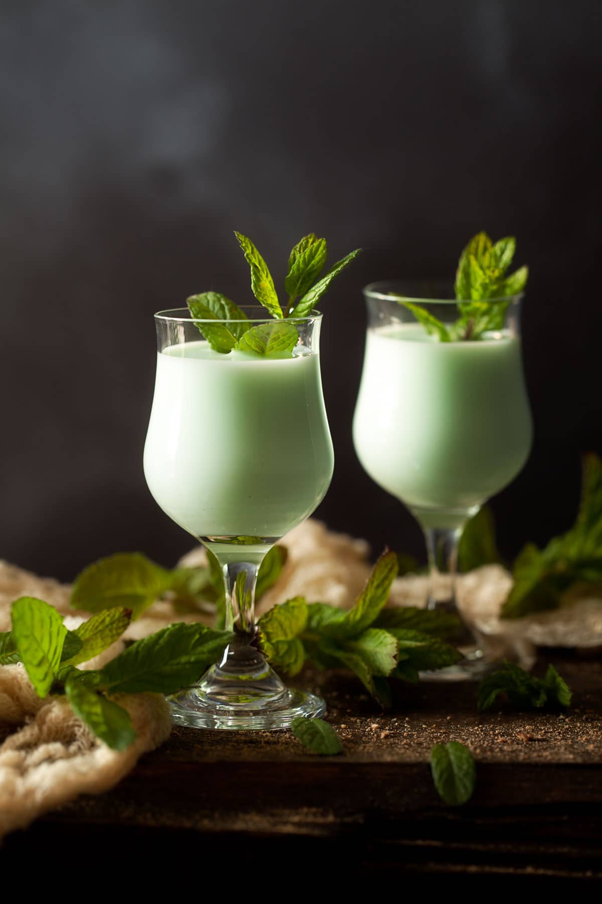 Pastel green creamy cocktails in 2 vintage glasses with mint leaves