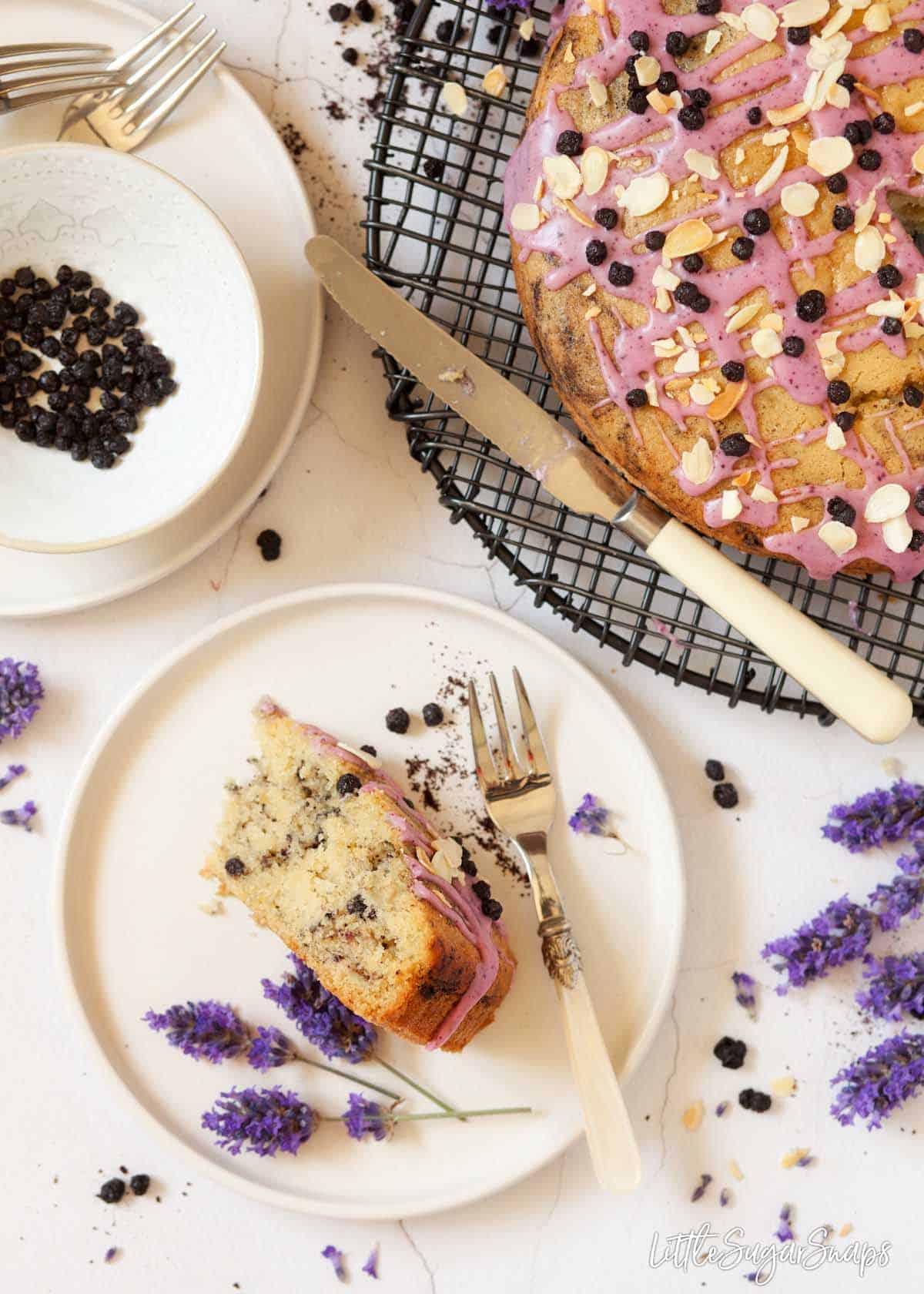 A slice of eggless blueberry cake on a plate with fresh lavender