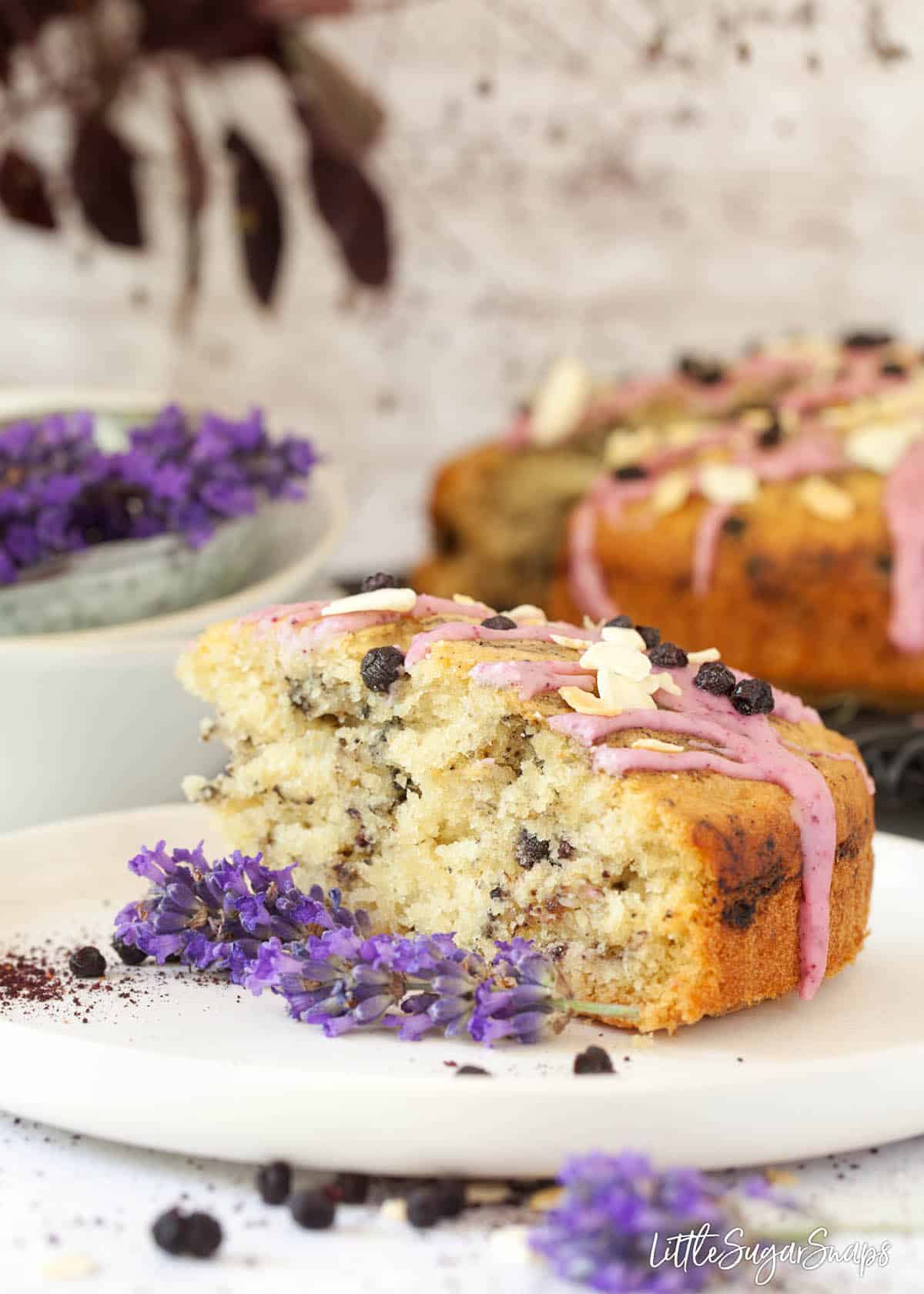 A slice of vegan blueberry cake on a plate with fresh lavender