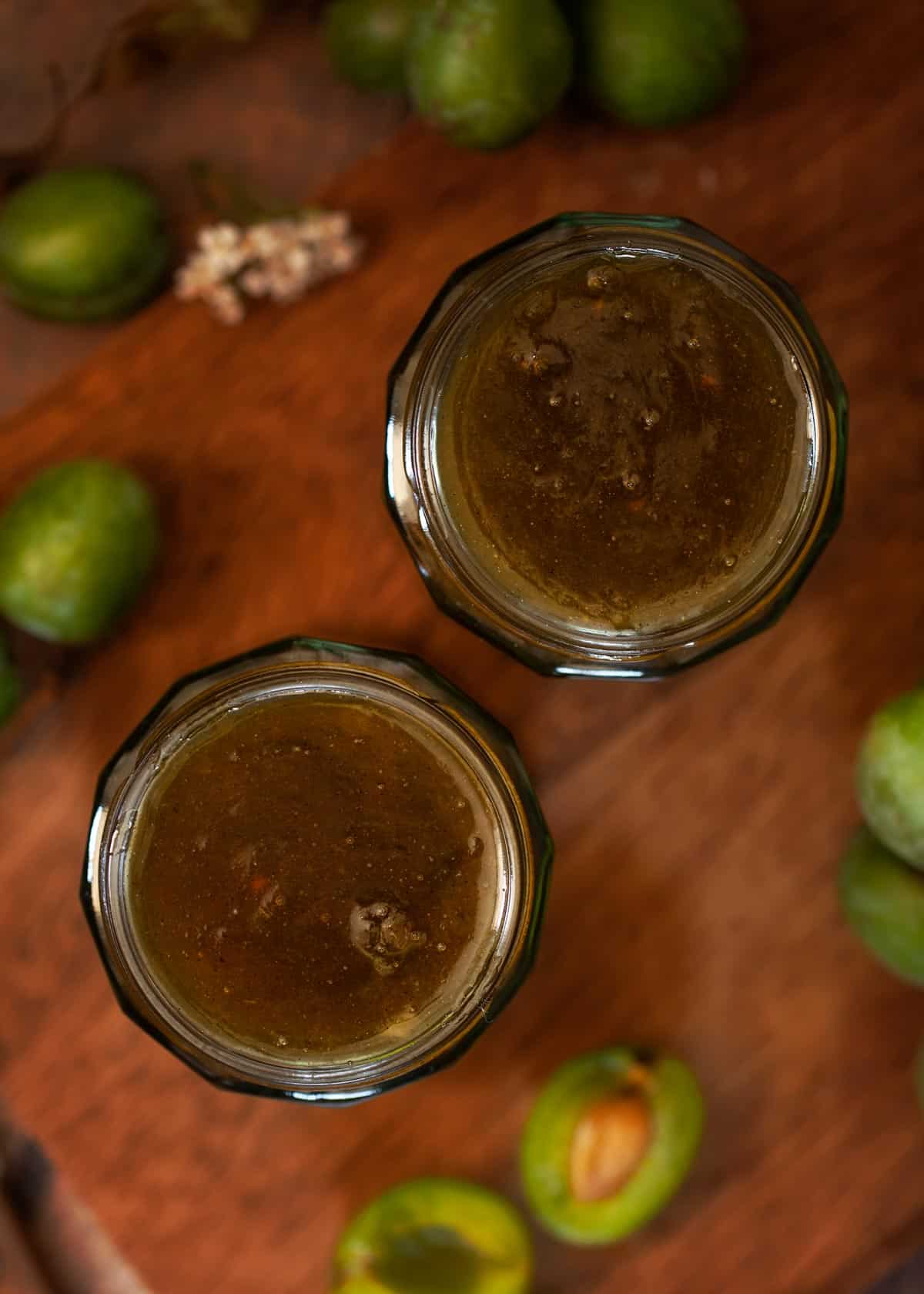 Two freshly filled jars of greengage jam ready to be sealed.