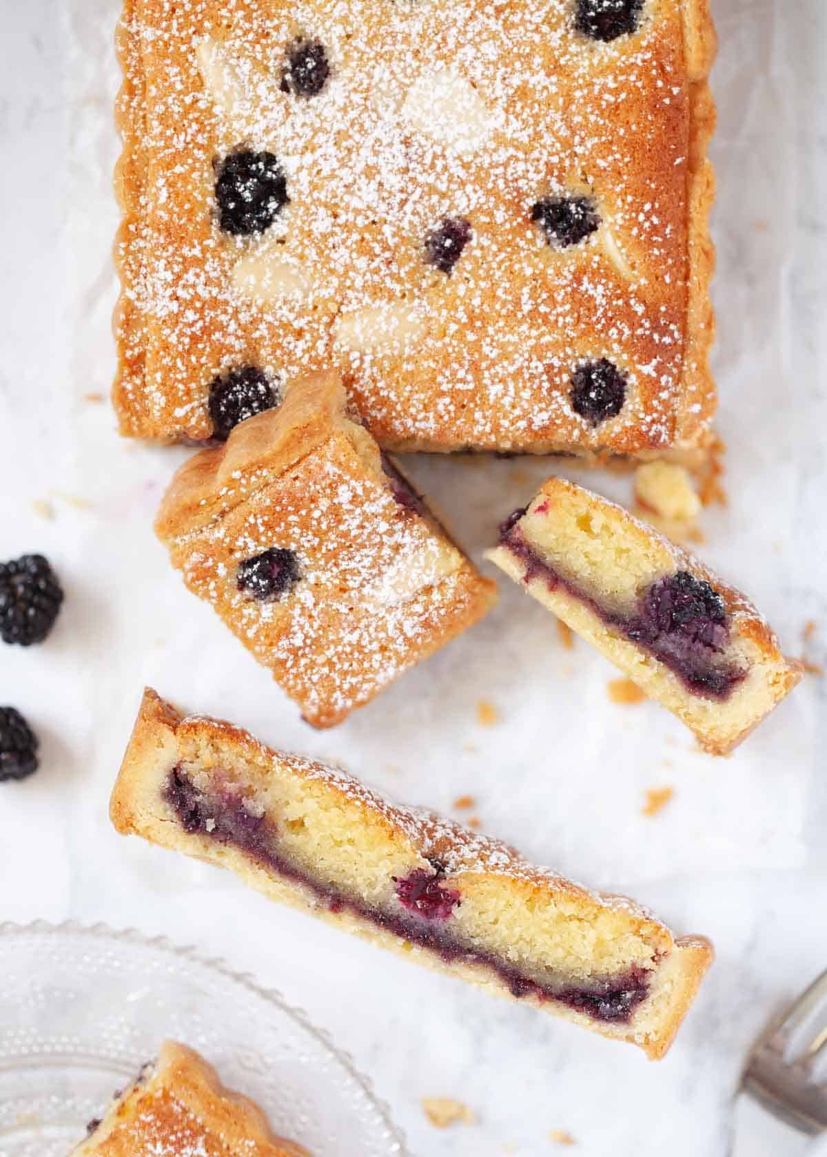 Part sliced almond frangipane tart with blackberries and jam