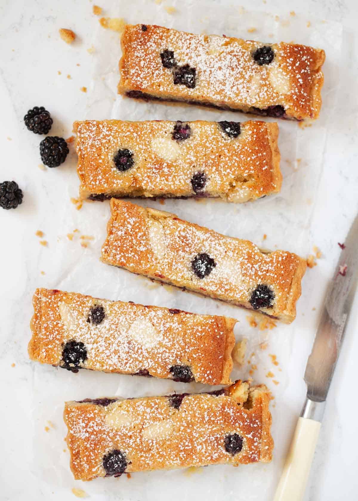 Five slices of blackberry and almond frangipane tart on a worktop