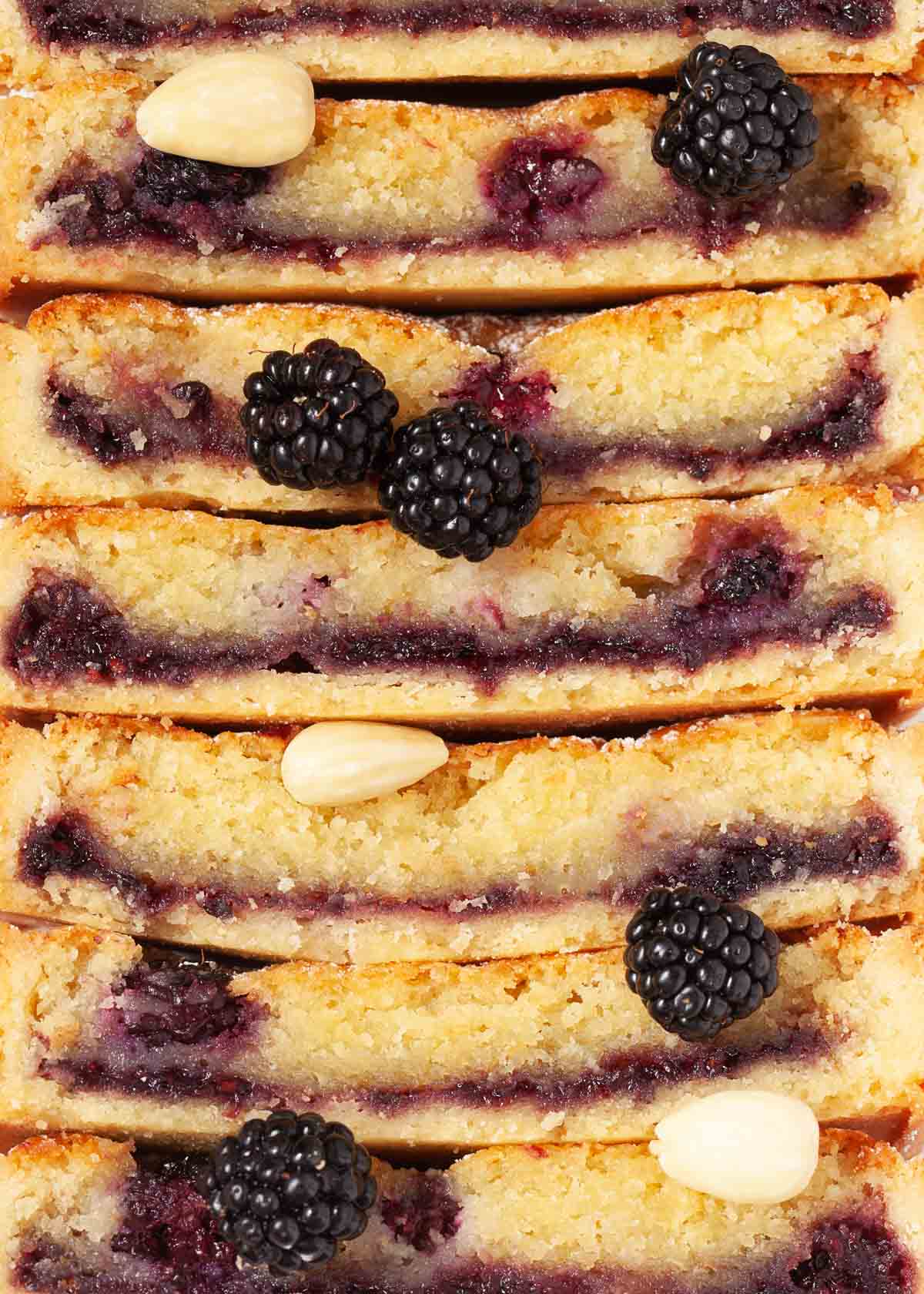 Close up of stacked up almond frangipane tart slices with blackberries
