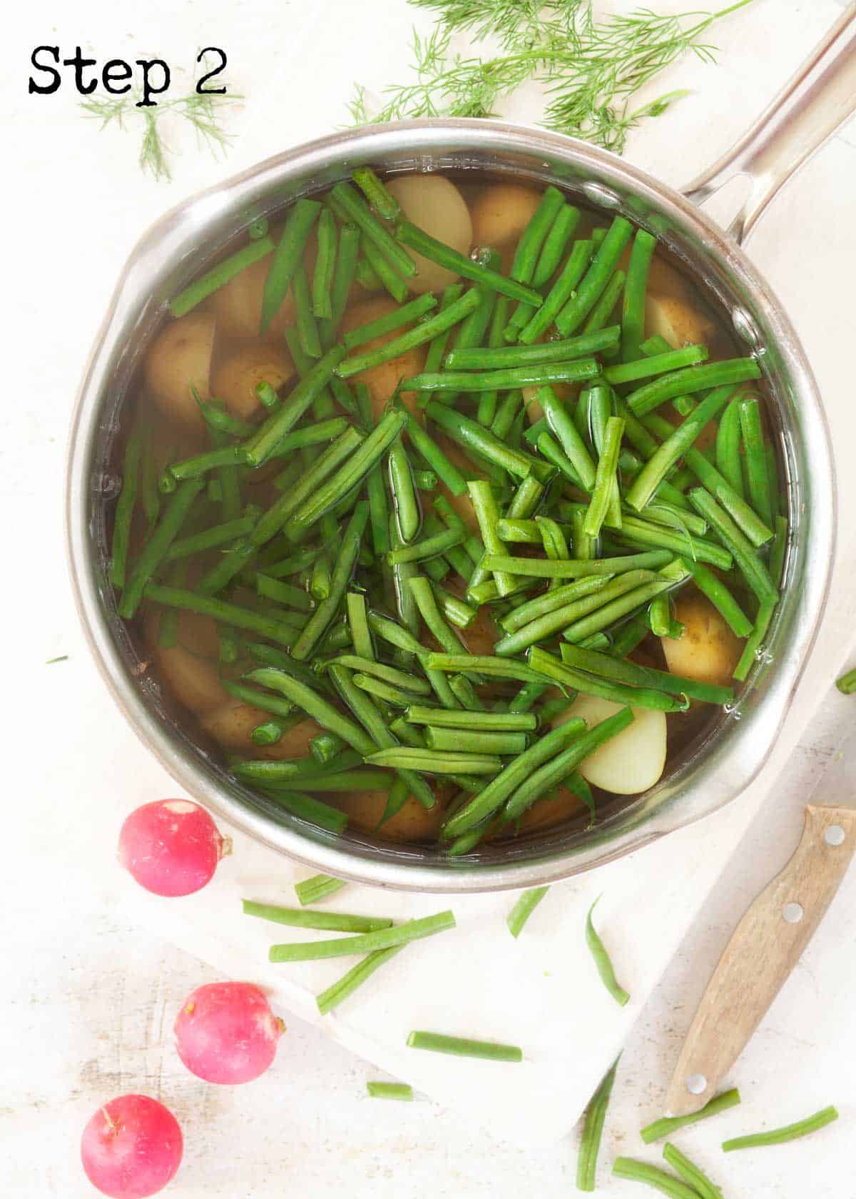 Process image - green beans added to a pan of cooked potatoes