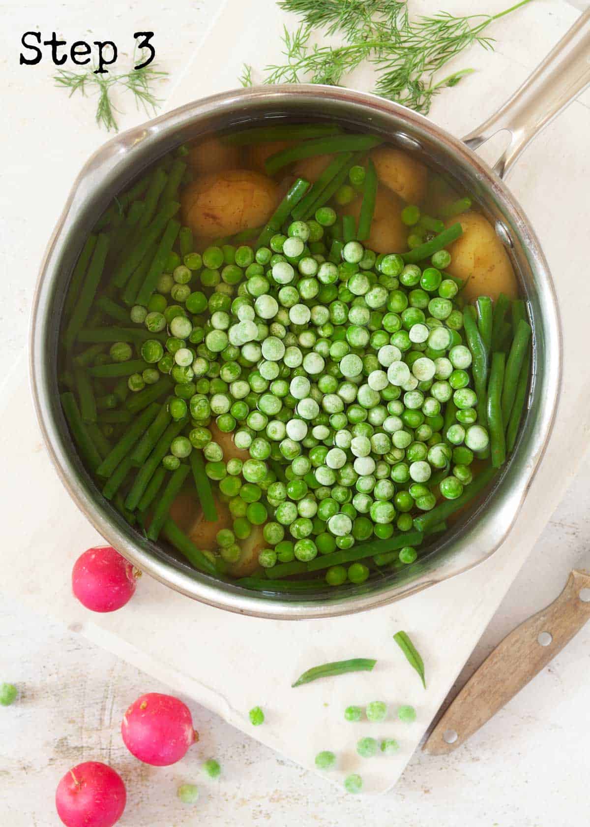 Process image - frozen peas added to a pan holding potatoes and green beans