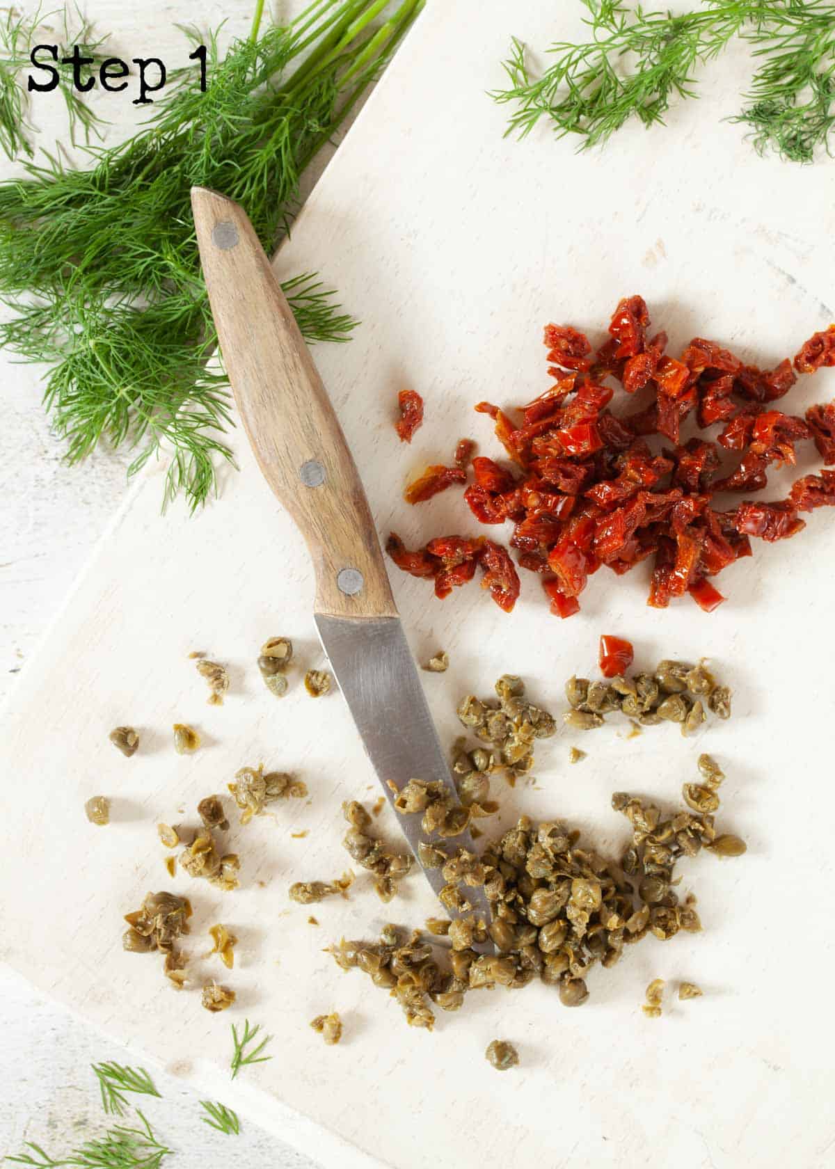 Process image - capers and sundried tomatoes chopped on a wooden board