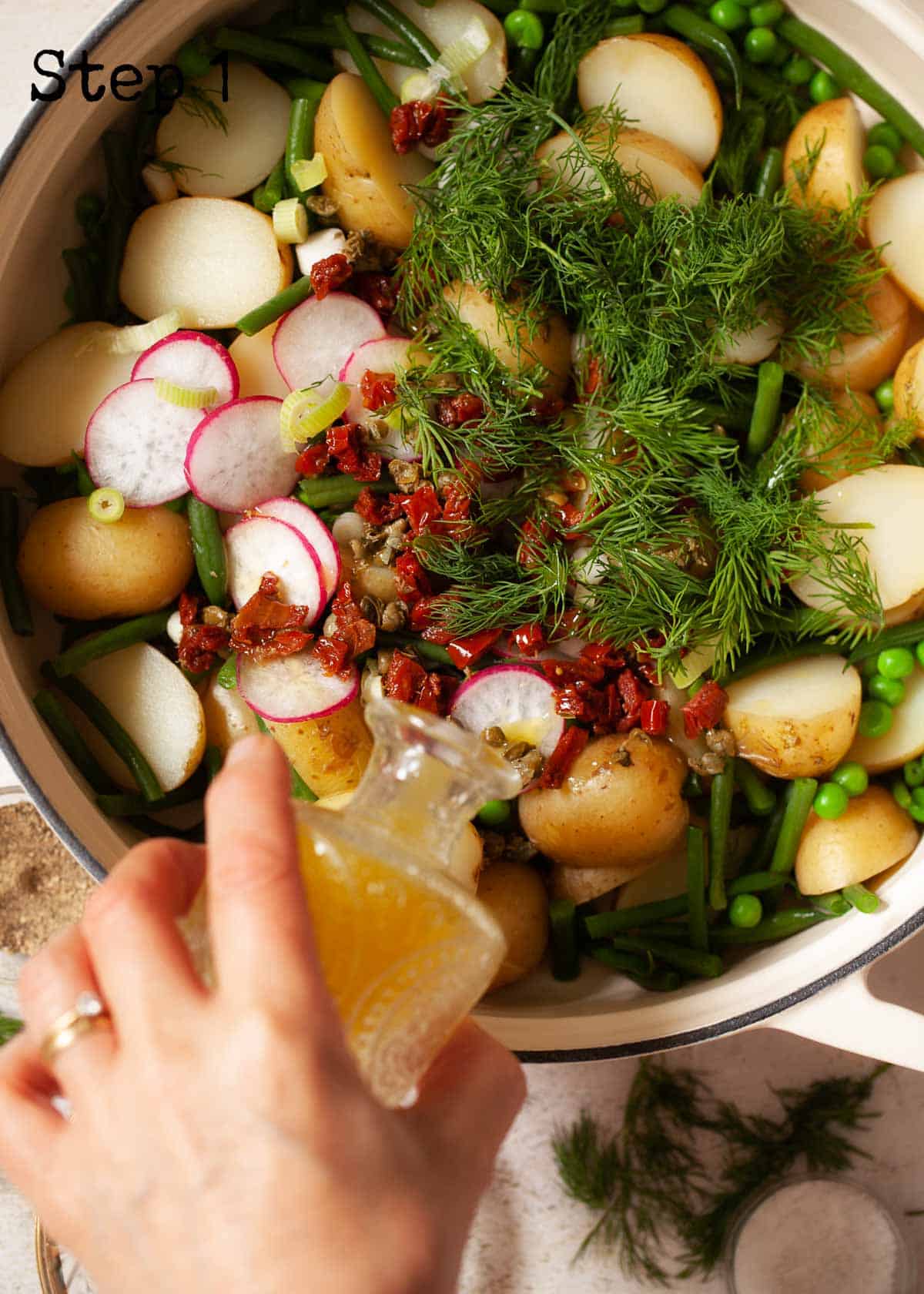 Process image - pouring vinaigrette over a bowl of salad ingredients