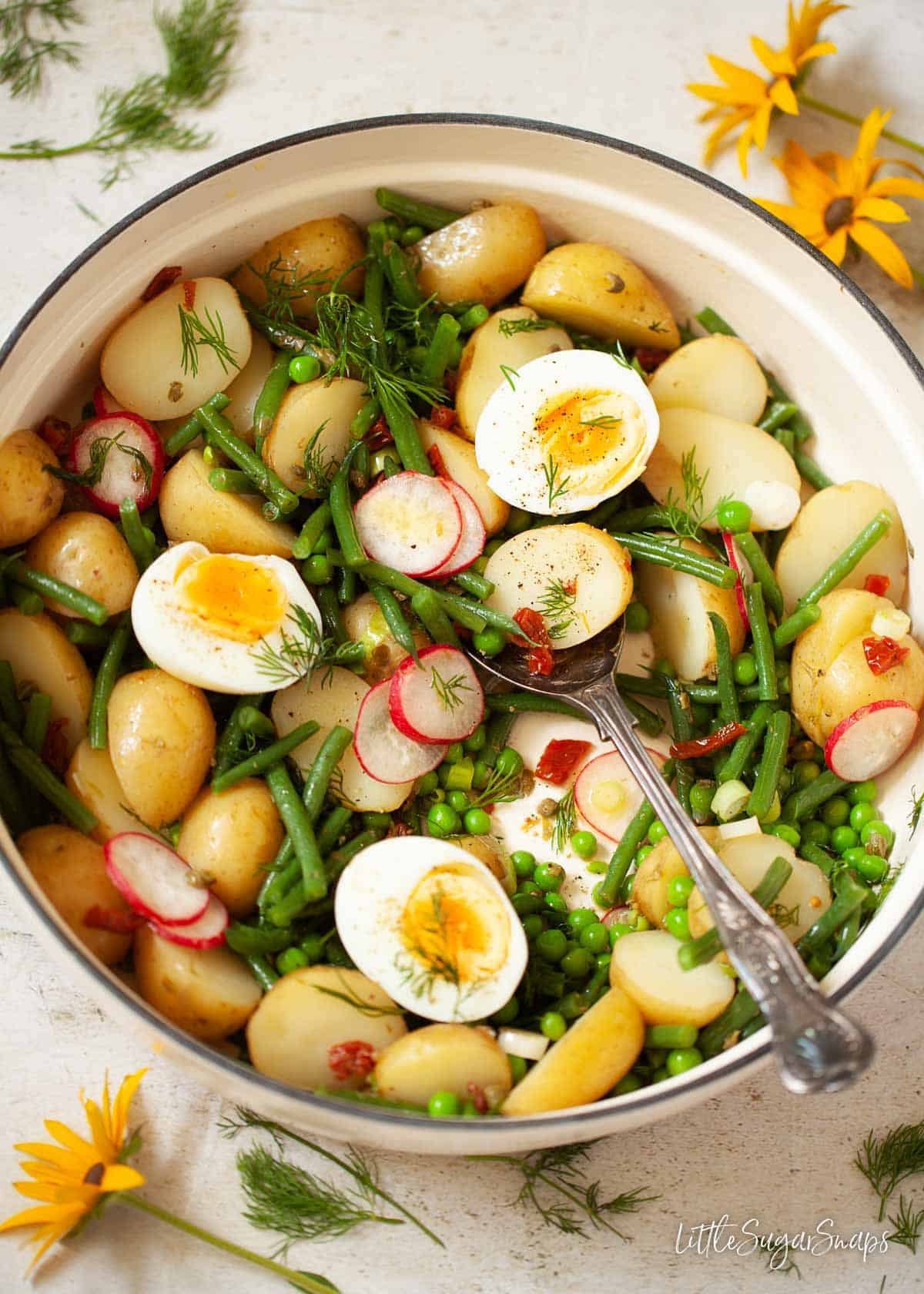 A pot of green bean and potato salad topped with hard boiled eggs