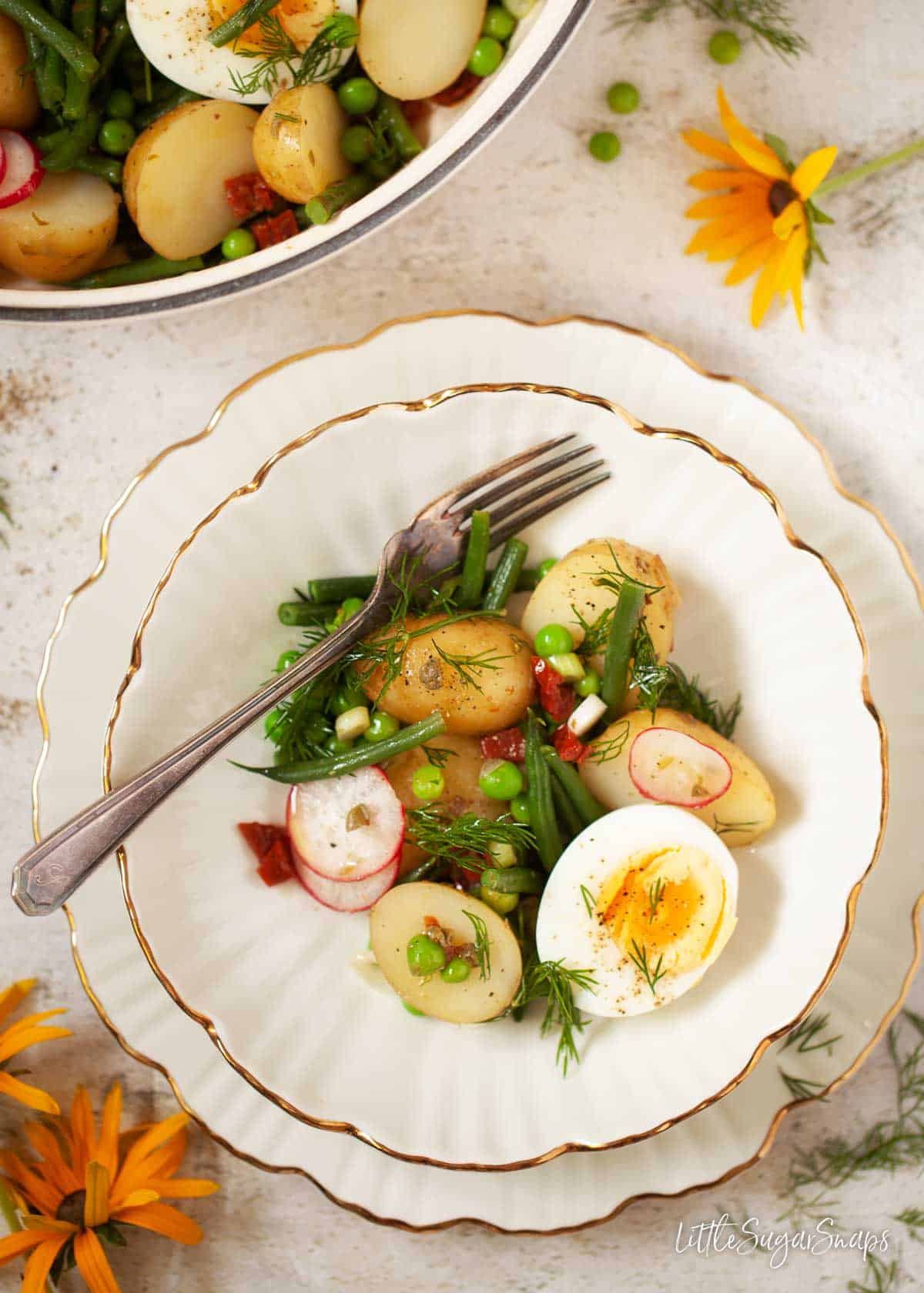 A serving of potato salad with half an hard-boiled egg on a fluted plate