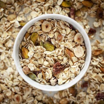 A bowl of muesli on a baking sheet with more muesli on it