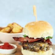 A bacon and cheeseburger on a wooden board