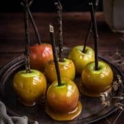 A tray of toffee apples with twigs in place of lollipop sticks