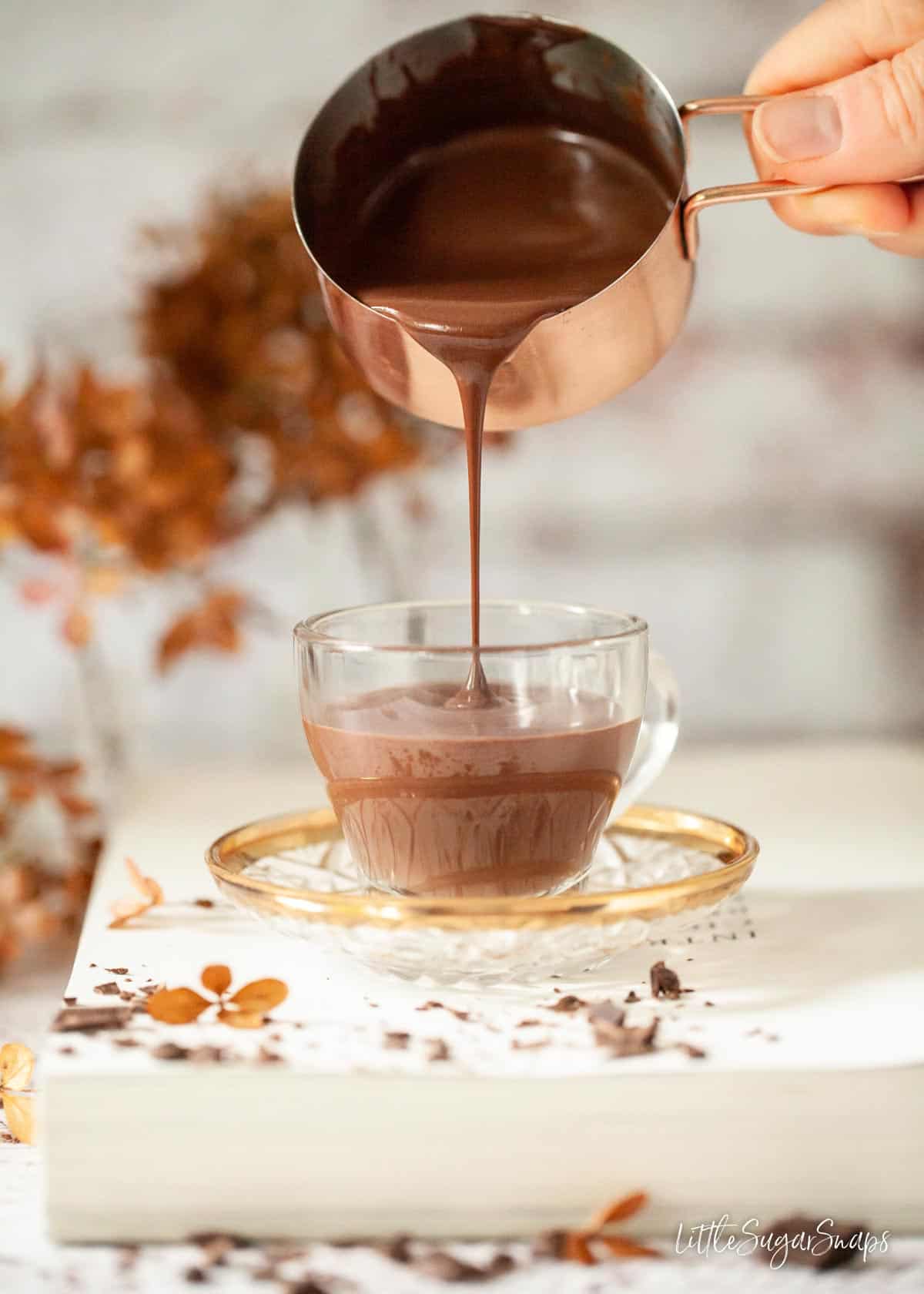 Italian cioccolata calda being poured into a glass cup