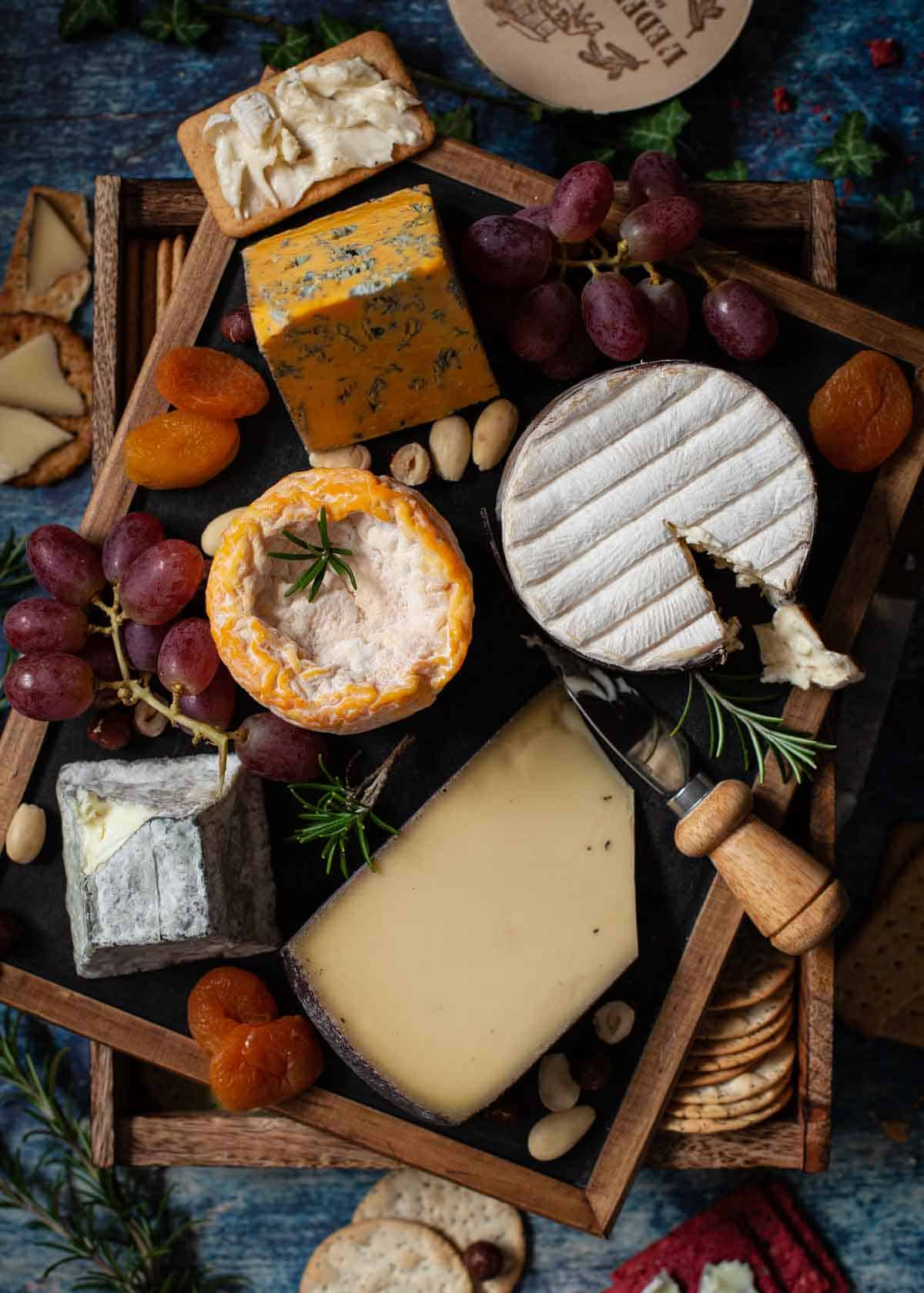 A cheese board with a tray of crackers, fruit and nuts