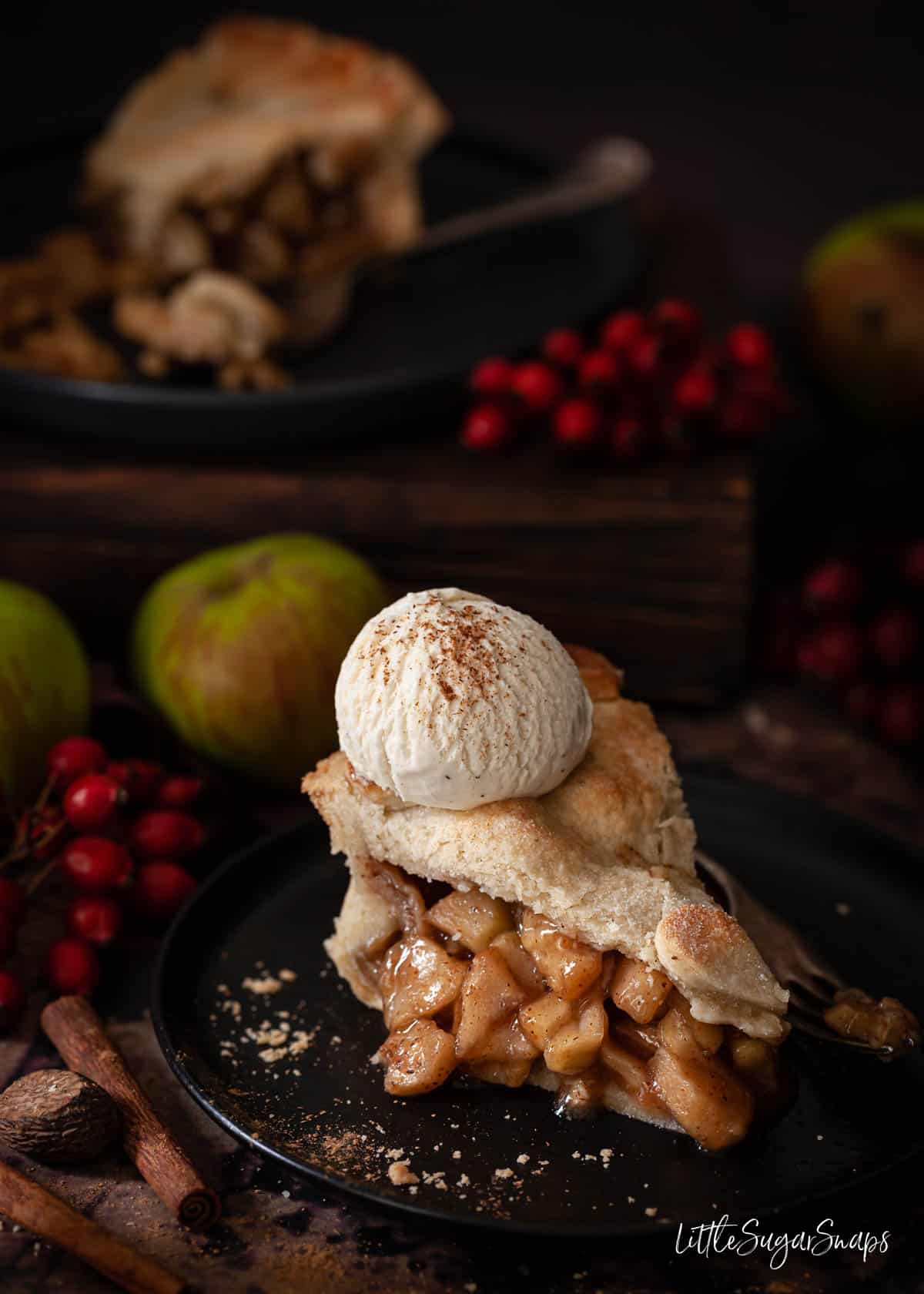 A slice of vegan apple pie with dairy free ice cream on top