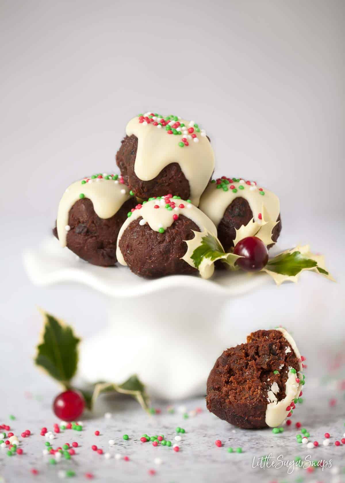 Christmas pudding chocolates on a small white cake stand. One has been bitten into.