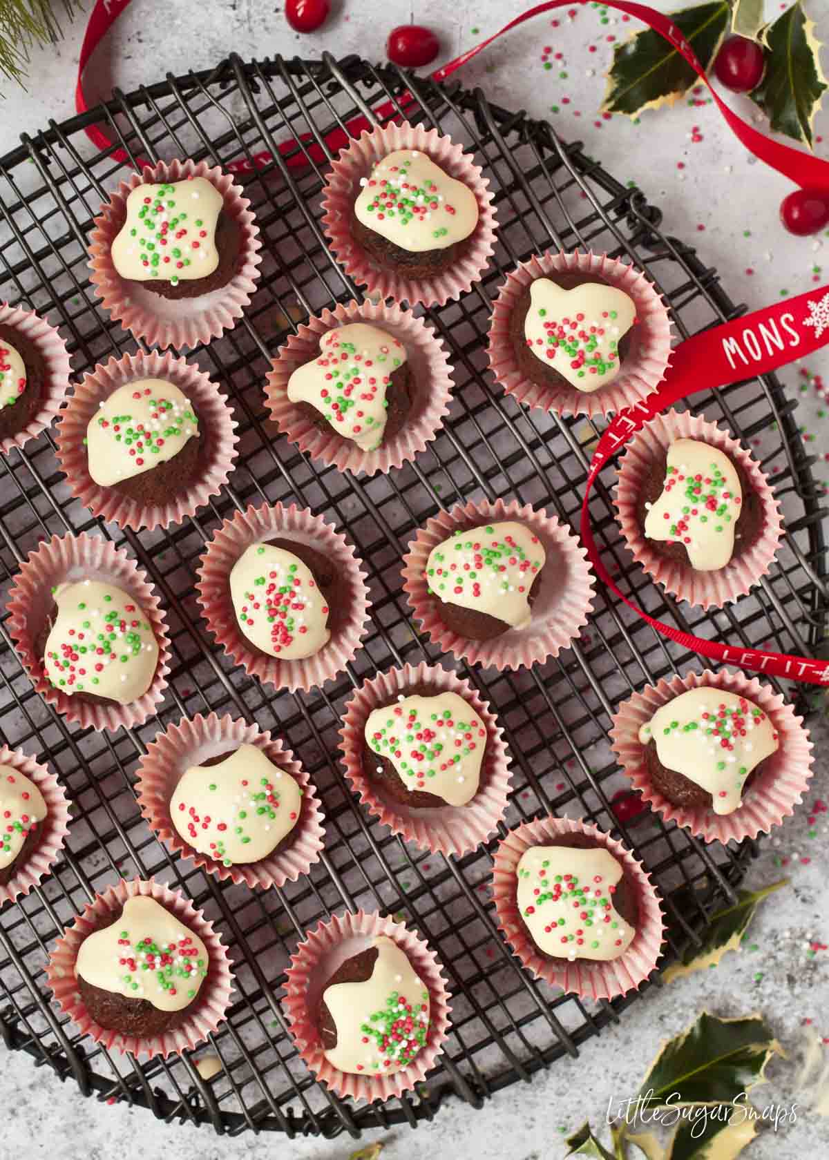 Christmas pudding truffles with white chocolate and sprinkles on a wire rack