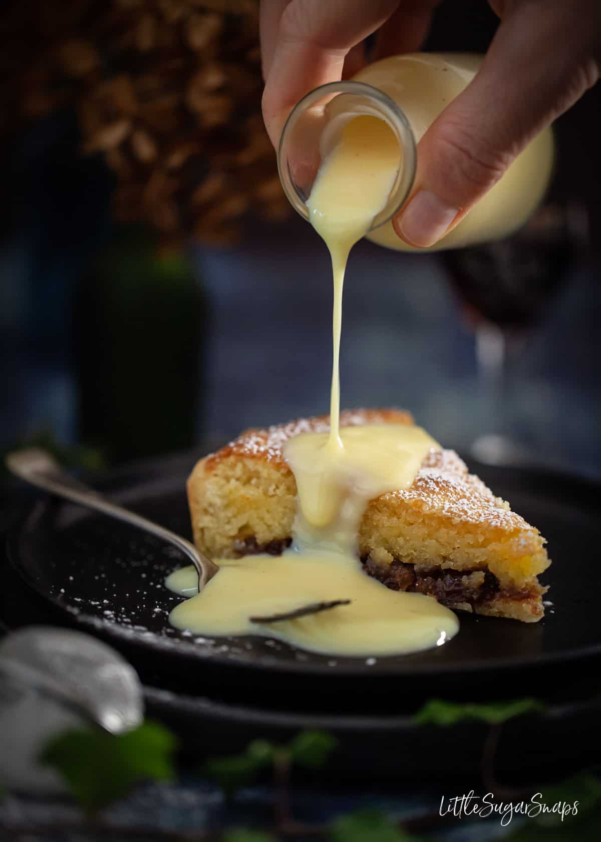 Person pouring custard over a slice of mincemeat tart with frangipane