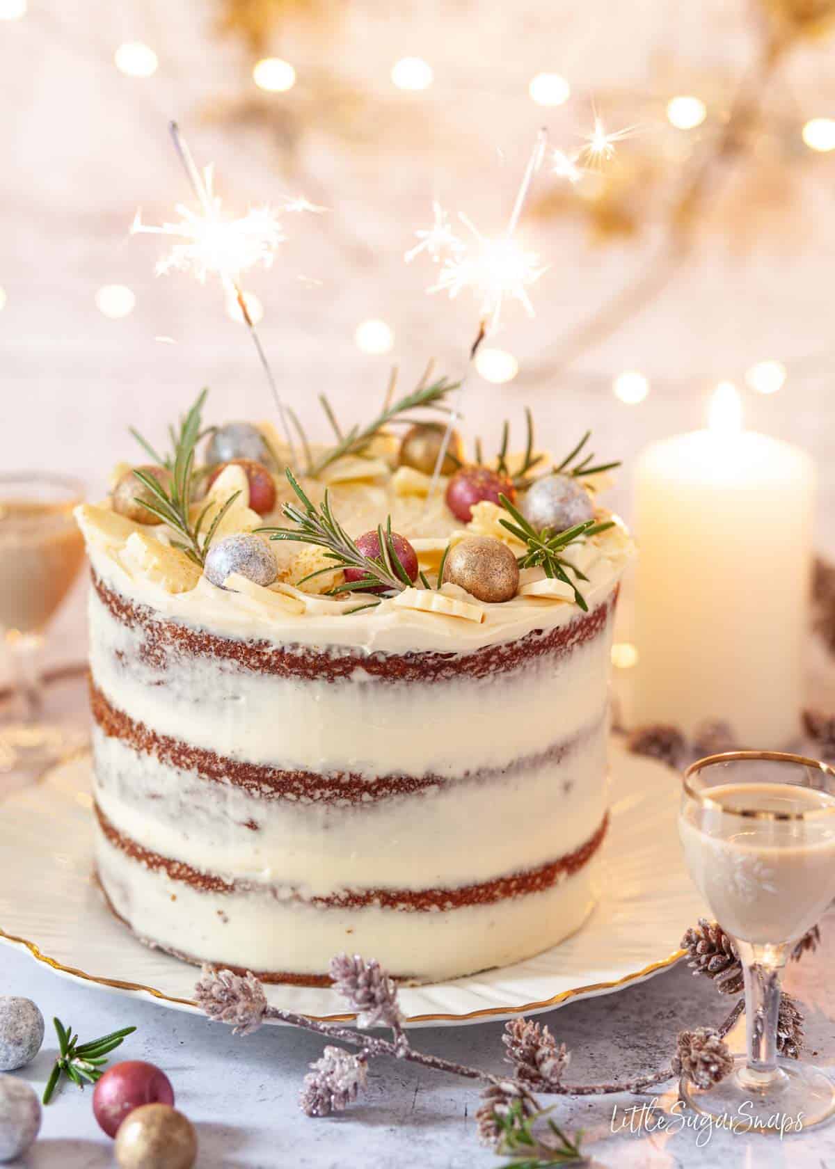 A naked White chocolate Baileys cake decorated with mascarpone frosting, chocolates and rosemary