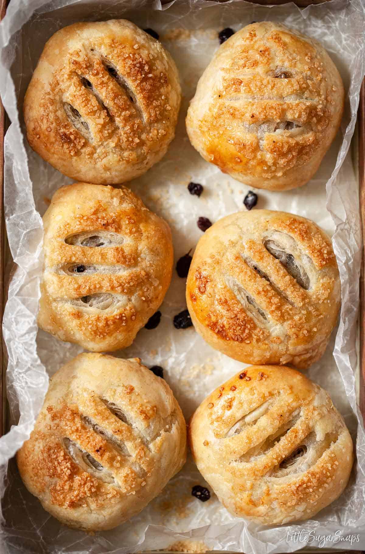 Six freshly baked Eccles cakes on waxed paper