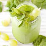 A green grape smoothie topped with fruit and mint