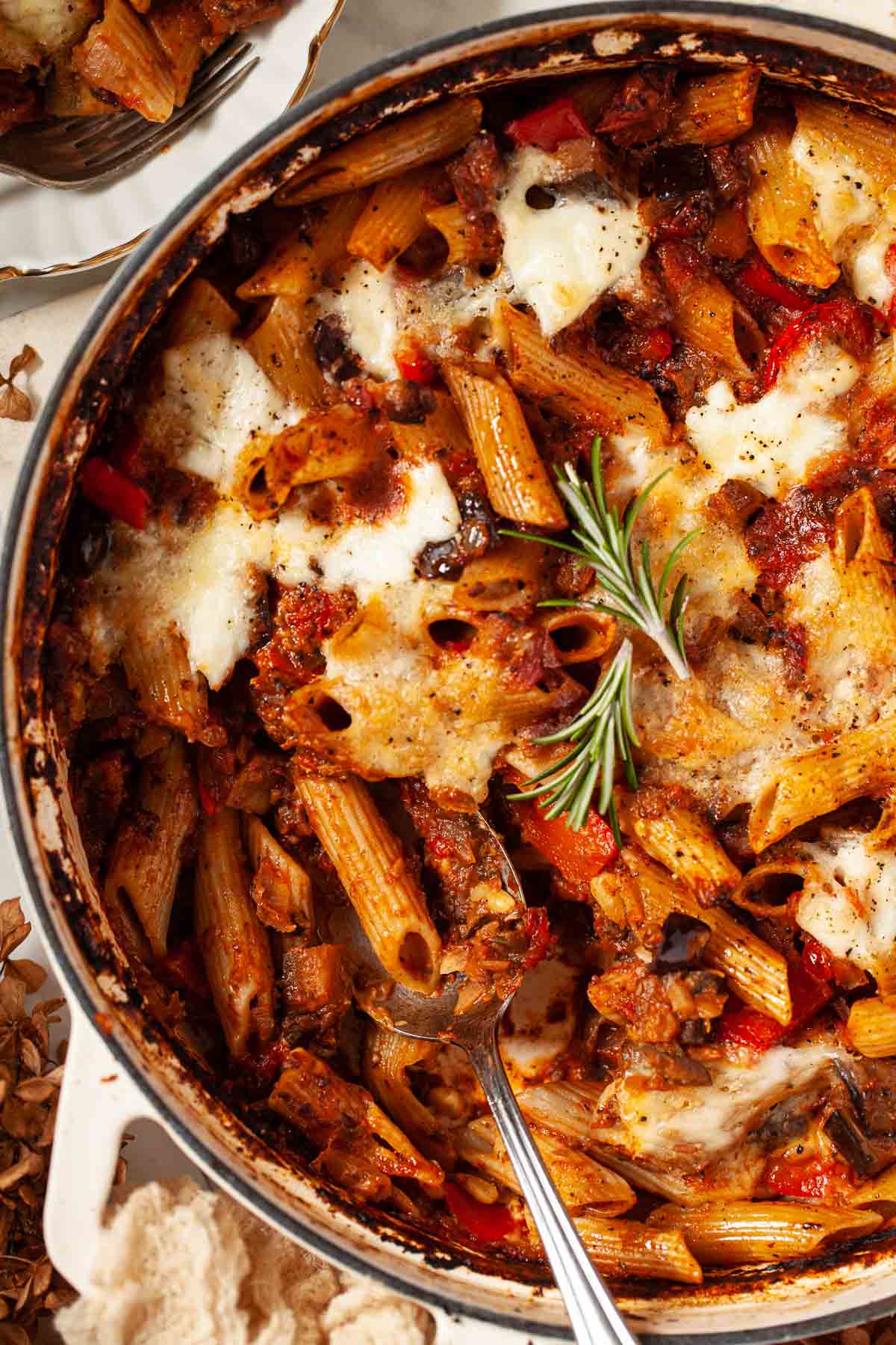 Close up of pasta al forno in a large serving pot with a spoon in it