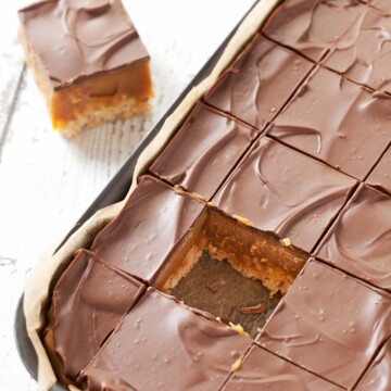 A tray of chocolate and caramel rice Krispie bars with a piece removed.