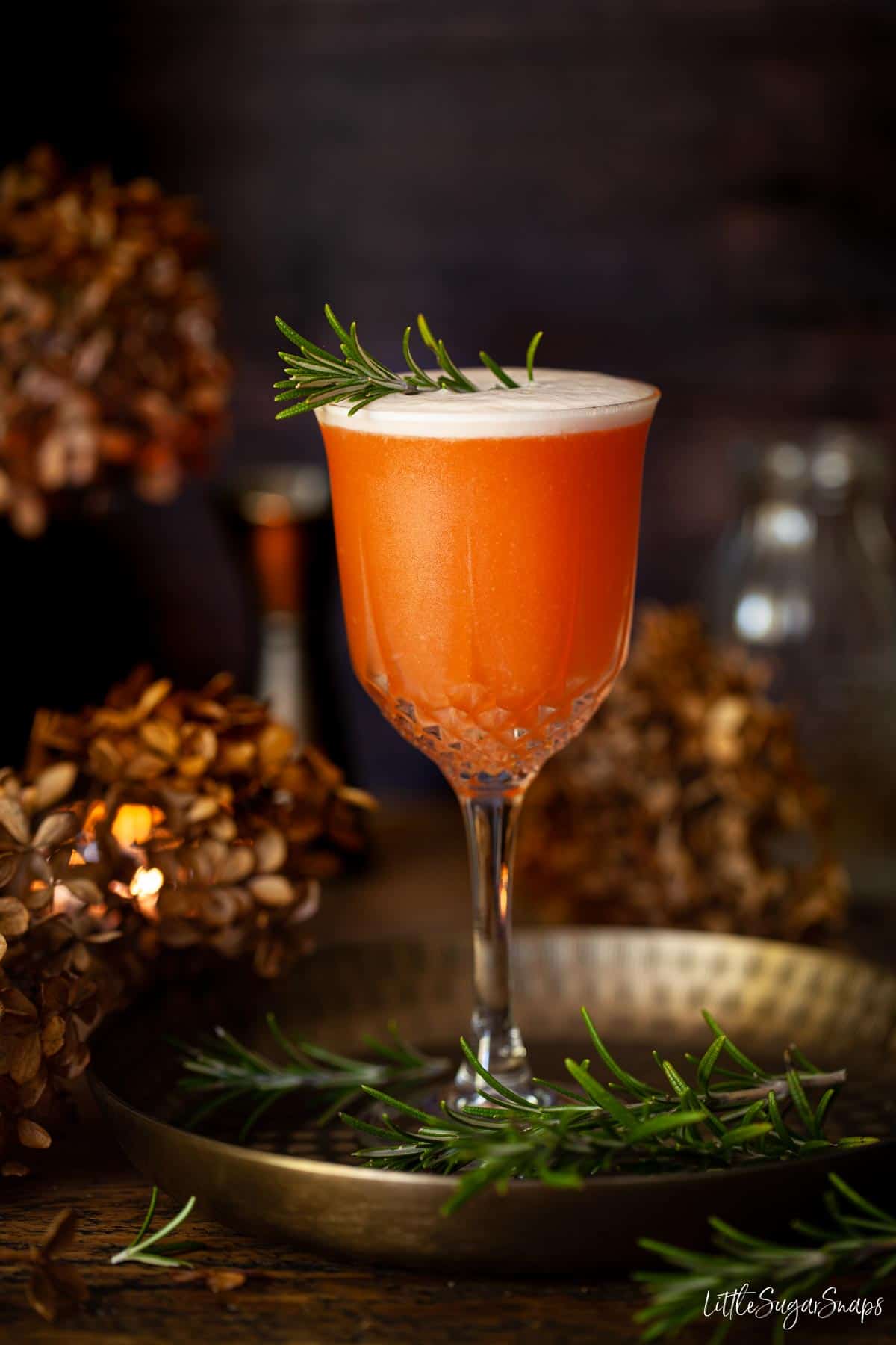 Straight on photo of Aperol sour gin cocktail with rosemary garnish