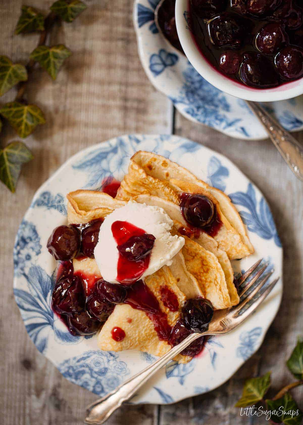 A plate of pancakes with cherries jubilee and ice cream