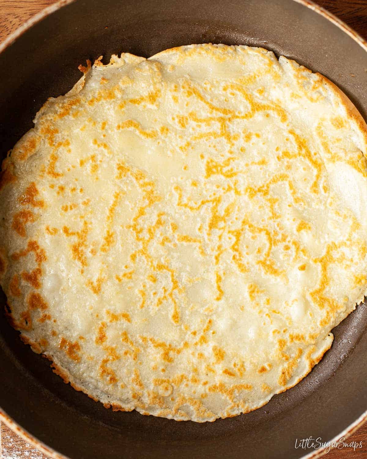 Cooked thin pancake batter in a frying pan