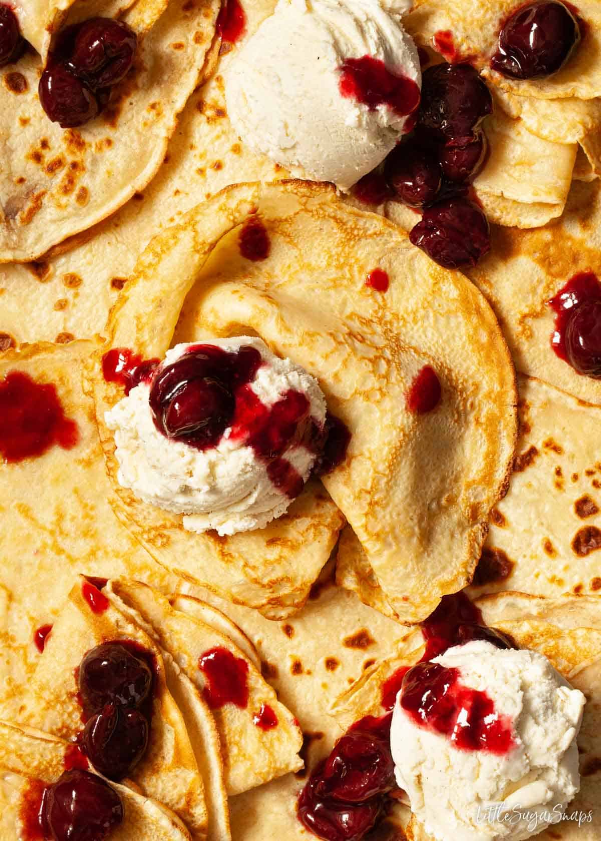 A platter of thin English pancakes with cherries jubilee and vanilla ice cream