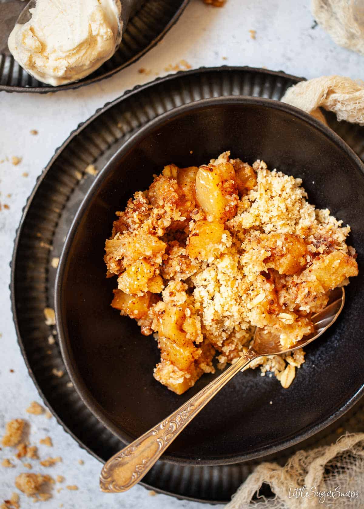 A serving of pineapple crumble in a black bowl