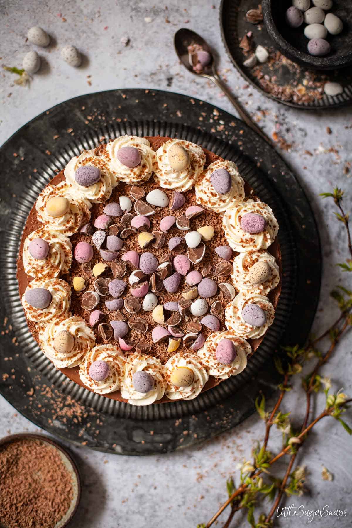 A no-bake Easter egg Cheesecake with whipped cream, chocolate flakes and candy eggs