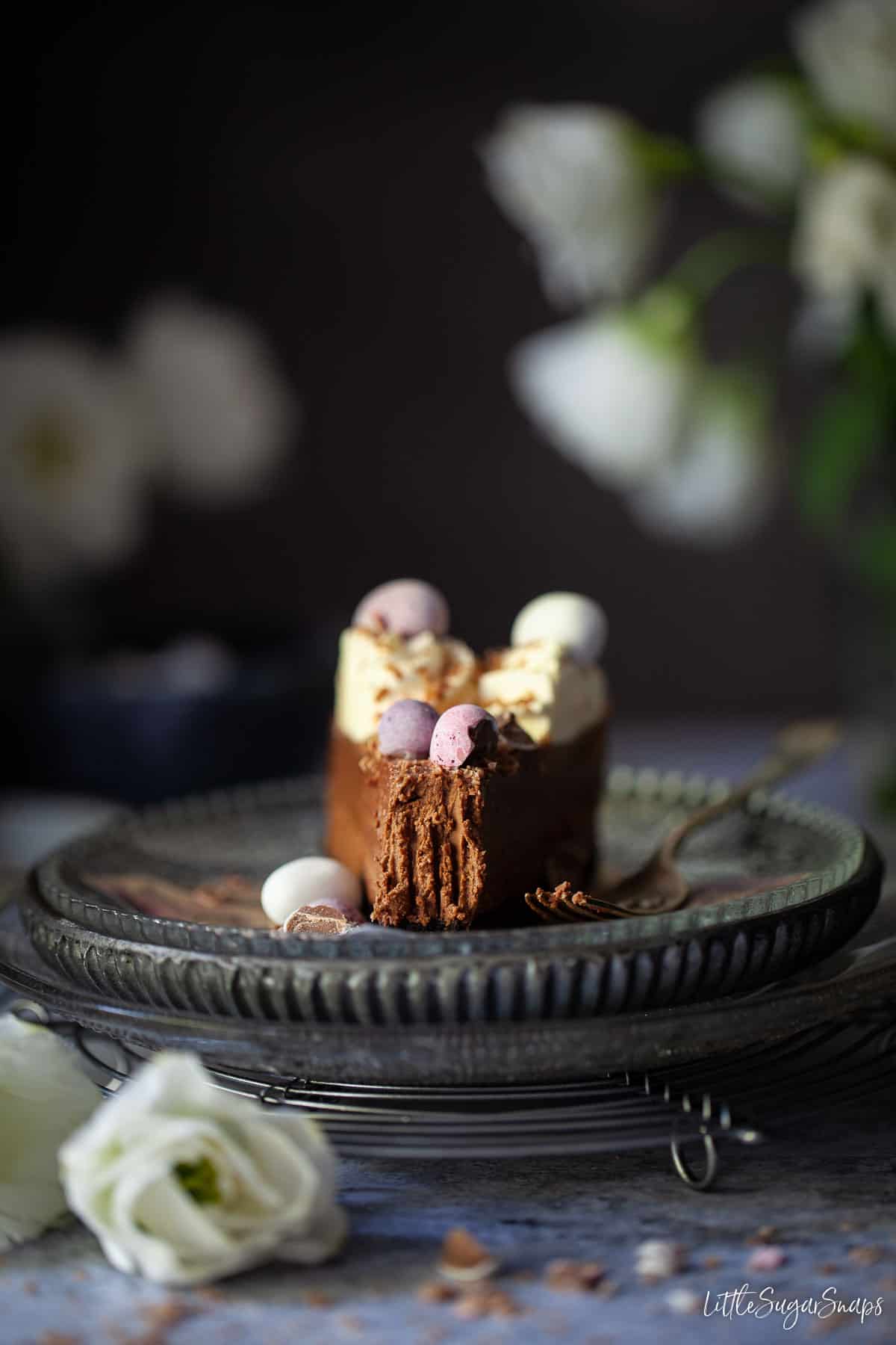 A part eaten slice of Easter egg cheesecake on a plate