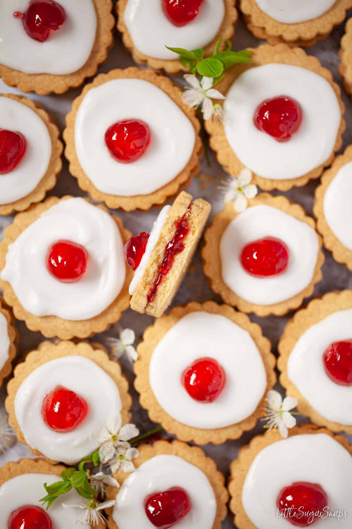 Close up of Empire biscuits with one on its side with a bite taken out revealing a jam centre