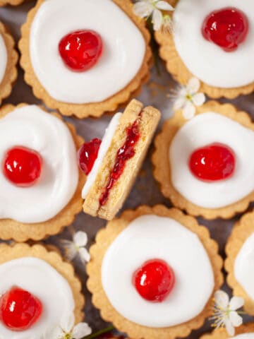 Empire biscuits close up with one on its side with a bite taken out showing the jammy centre