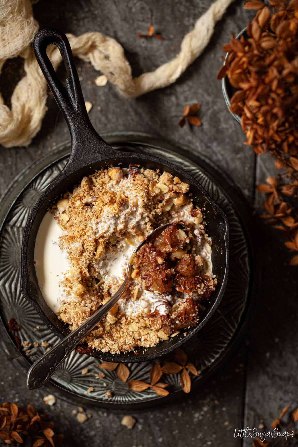 A single serve skillet of chocolate and pear crumble with pouring cream