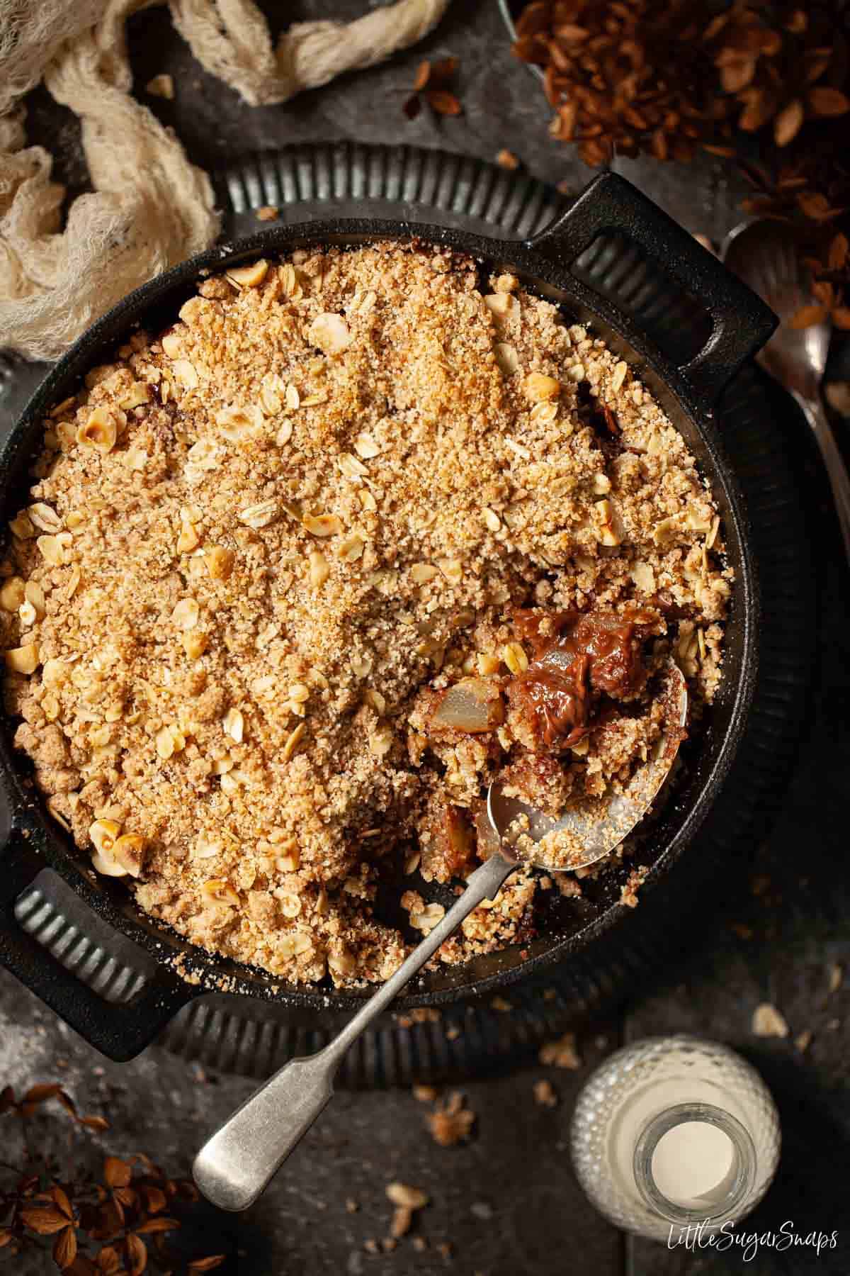 Chocolate and pear crumble in a cast iron skillet with a serving spoon in it