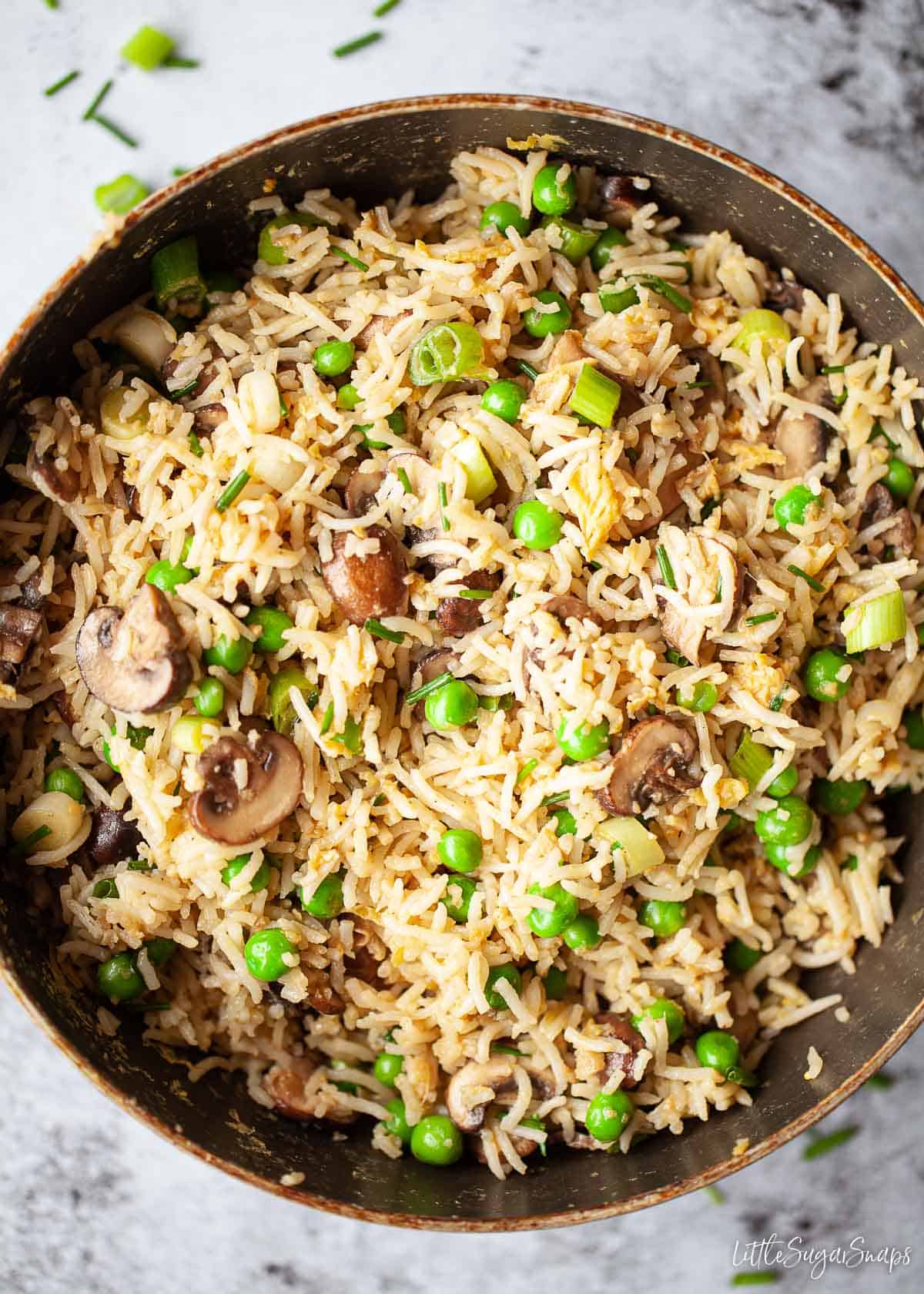 A pan of egg fried rice with mushrooms and peas