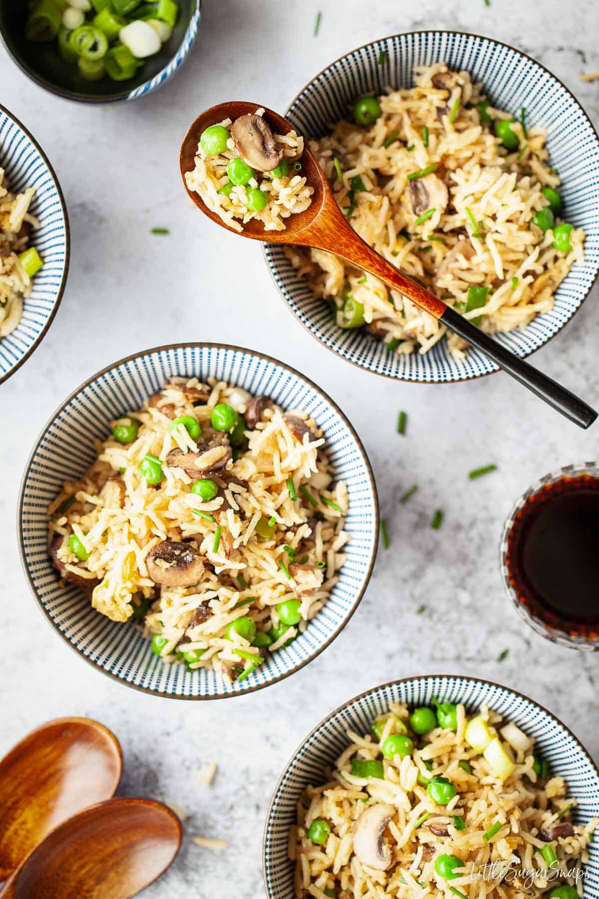 Three bowls of mushroom fried rice, one with a spoon across it.