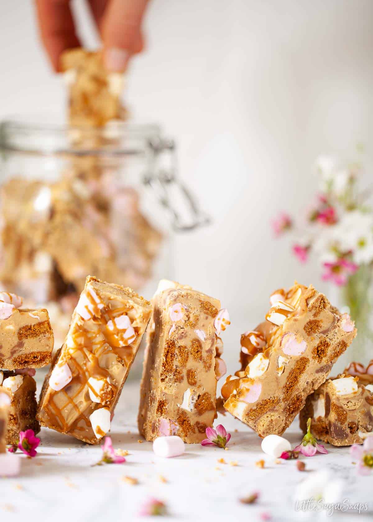 White chocolate and biscoff rocky road with a person taking a bar