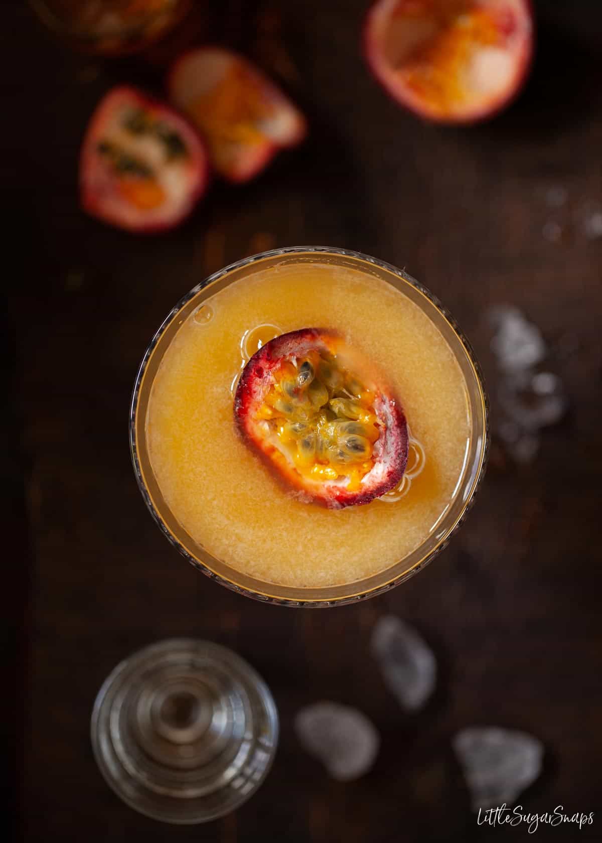 Overhead view of a passionfruit cocktail topped with fresh passionfruit