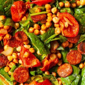 Close up of a roasted chickpea salad with spinach, tomato and chorizo
