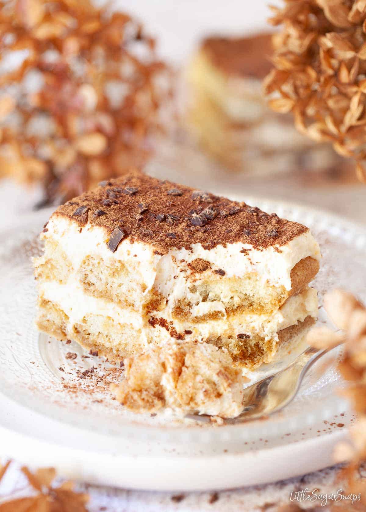 A piece of Italian tiramisu with a chunk taken out using a fork