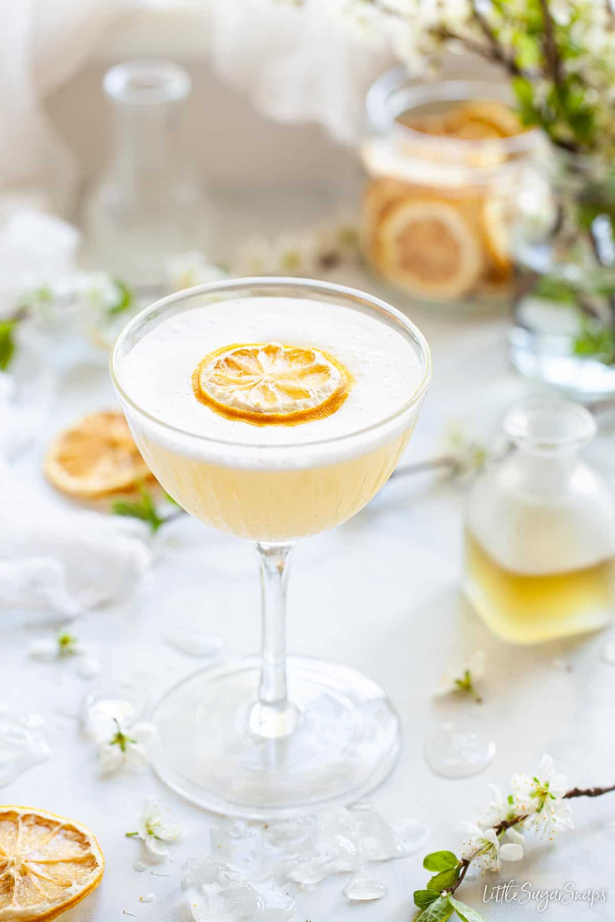 A camomile gin sour cocktail with dehydrated lemon wheel garnish