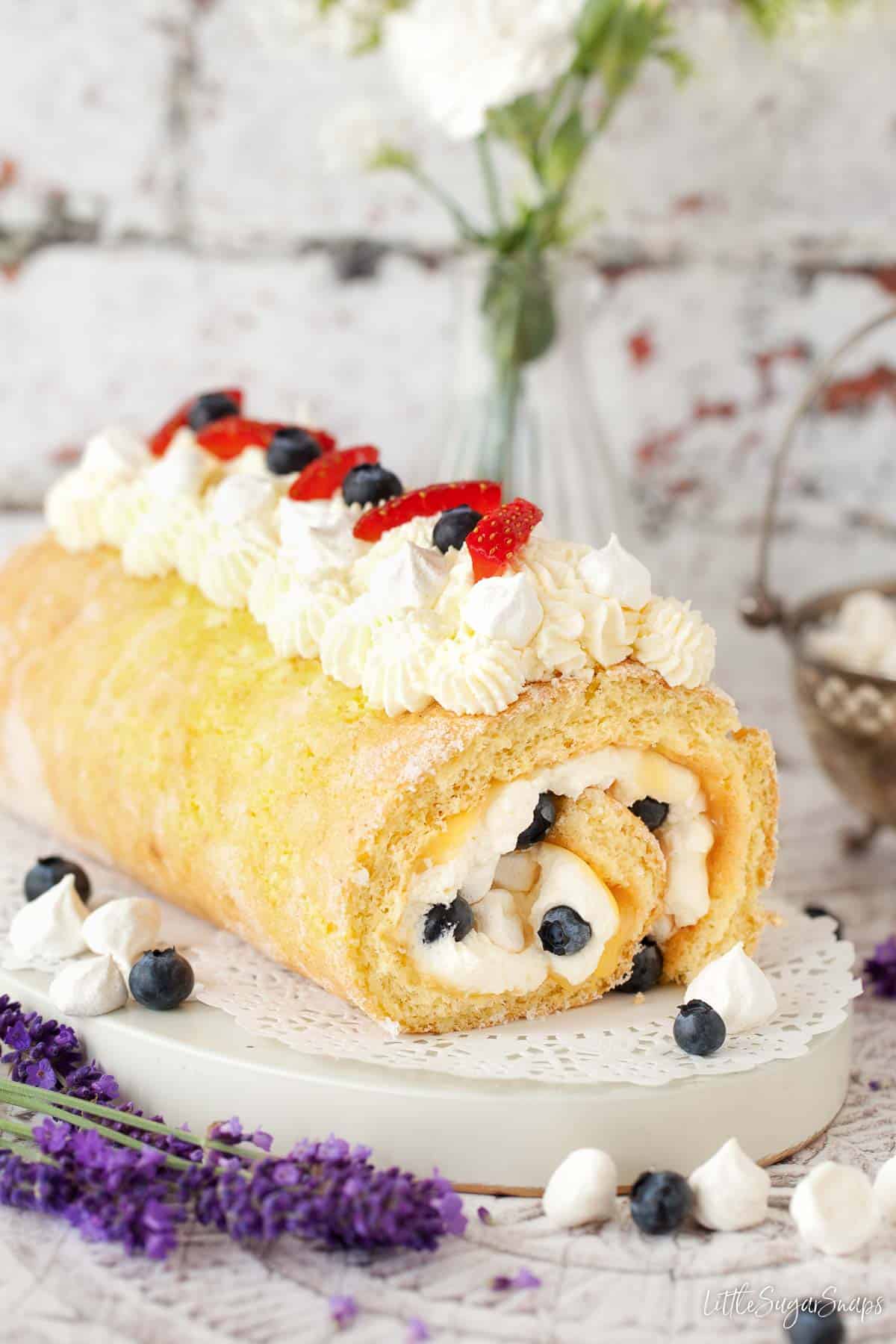 A lemon meringue swiss roll cake with fresh fruit and cream