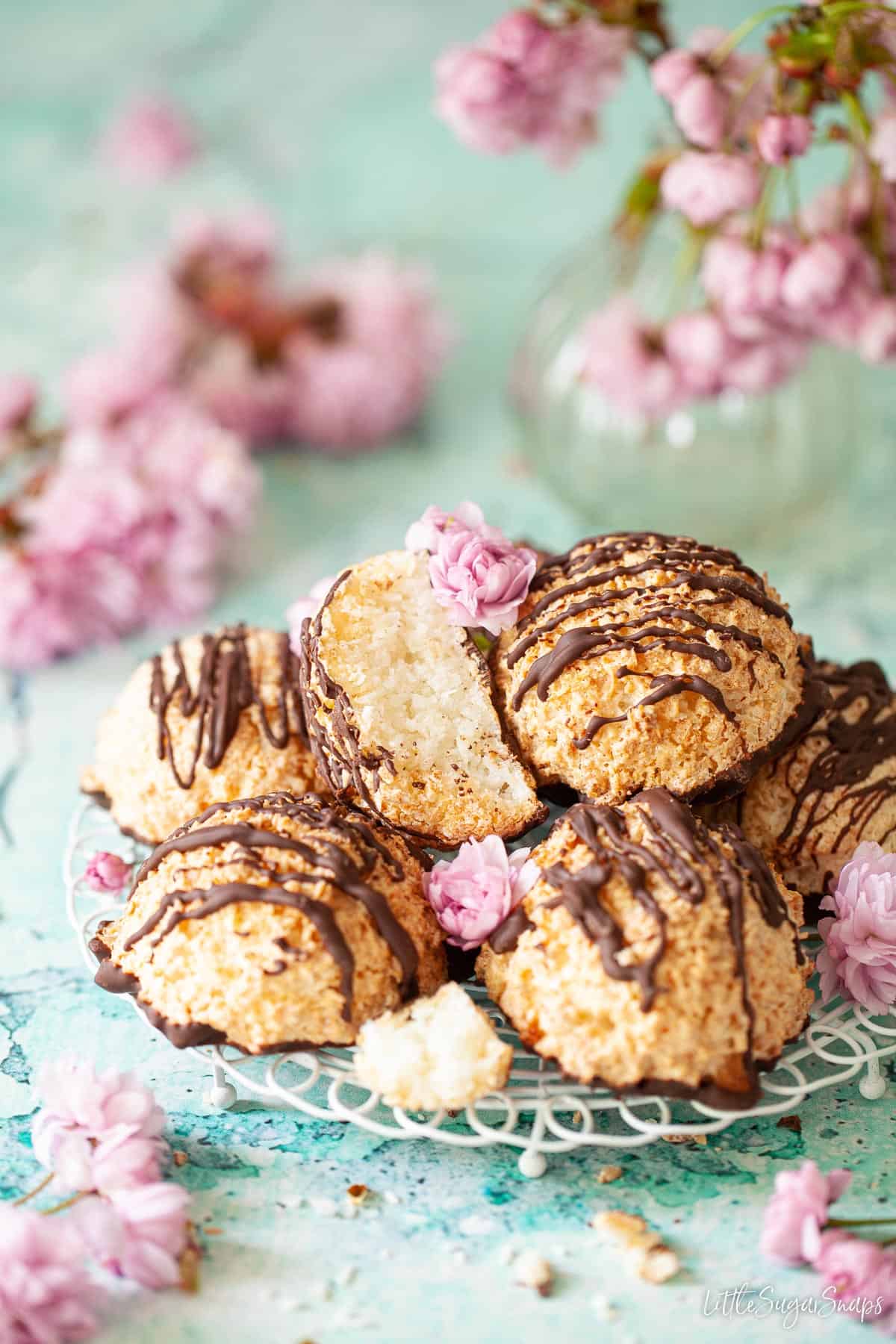 A plate of coconut macaroons with pink flowers surrounding it