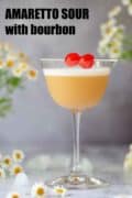 An Amaretto sour cocktail garnished with egg white foam and cocktail cherries