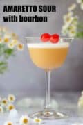 An Amaretto sour cocktail garnished with egg white foam and cocktail cherries