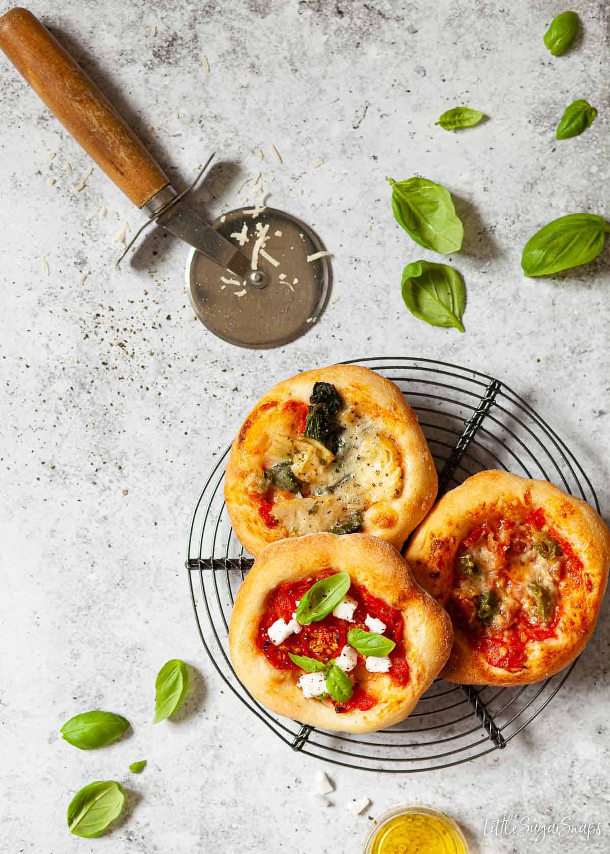 Assorted little pizzas on a worktop including a meat pizza, vegetarian pizza and a vegan pizza.